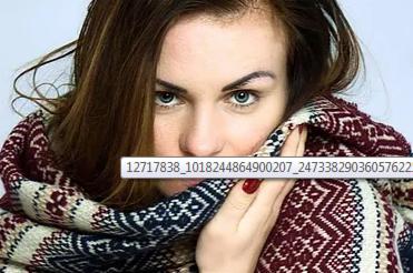 Portret kobiety z wyraźnym makijażem oczu, czerwonym lakierem na paznokciach i dużym wzorzystym szalikiem zasłaniającym część twarzy.