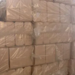 Stos kostek brykietu drzewnego, zapakowanych w przezroczystą folię, ułożonych warstwami, z widoczną fakturą drewna.