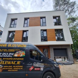 P.H.U. MAJSTER-BUD Jacek Kozłowski - Nowoczesny dom z ocieploną elewacją, wykończony drewnianymi panelami. Na pierwszym planie firmowy bus z reklamą usług ocieplania i wykończeń.