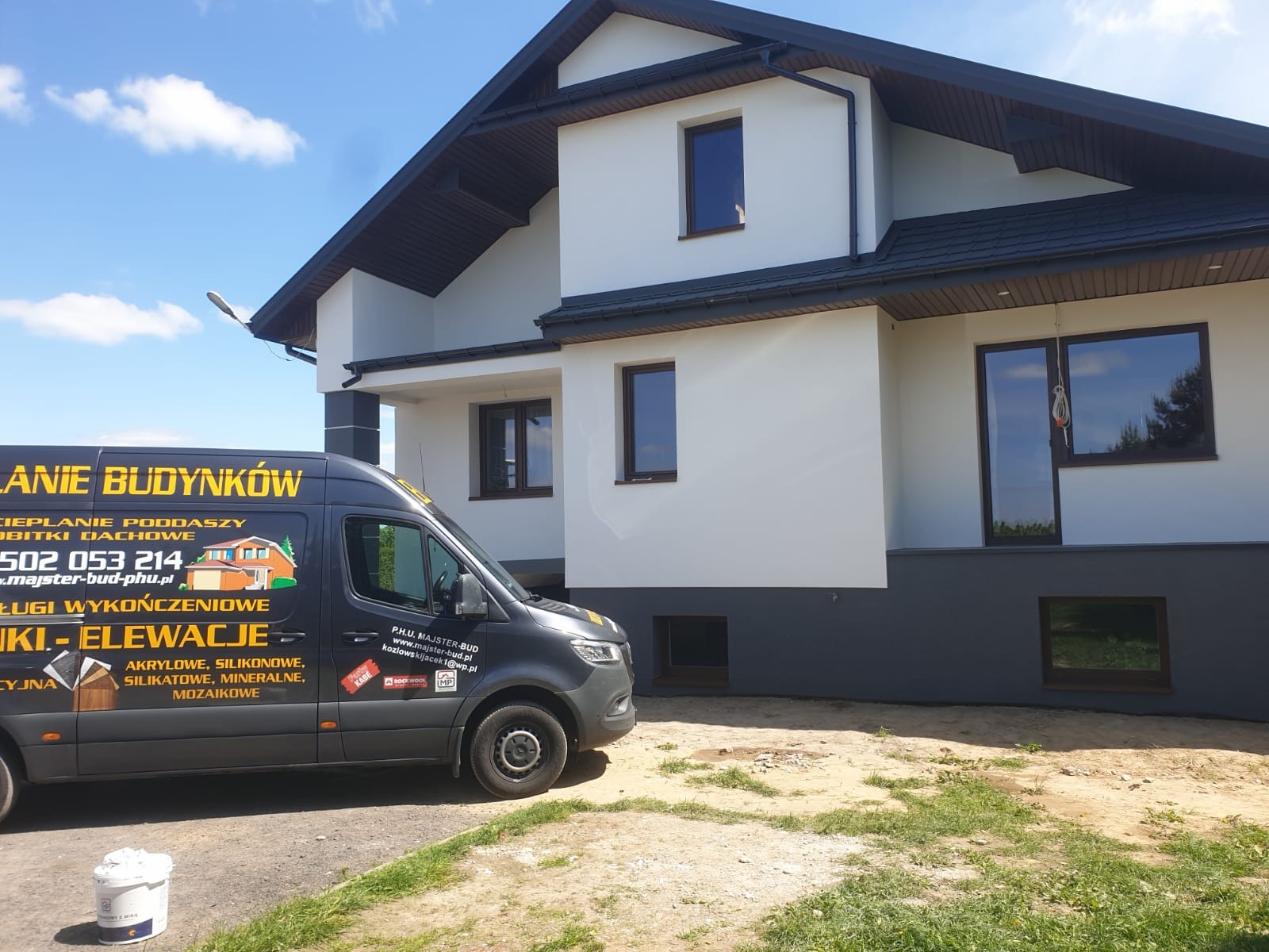 Nowoczesny dom po renowacji elewacji, z widocznym firmowym vanem z reklamą ocieplania budynków i elewacji. Dwukolorowa elewacja: biała góra i szary dół.