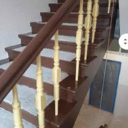 Odnowione drewniane schody z brązowymi stopniami i kremowymi balustradami, widok z g&oacute;ry, zabezpieczone okno w tle.