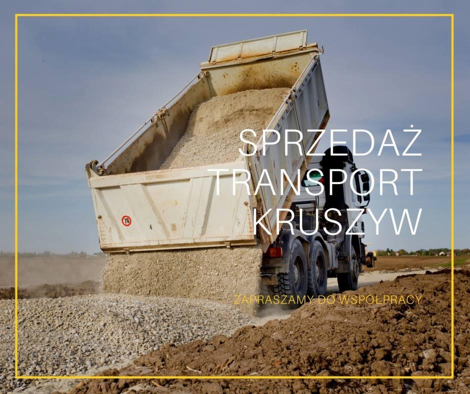 Ciężarówka wyładowuje kruszywo na placu budowy, widoczne koła i tylna część pojazdu, w tle błękitne niebo.