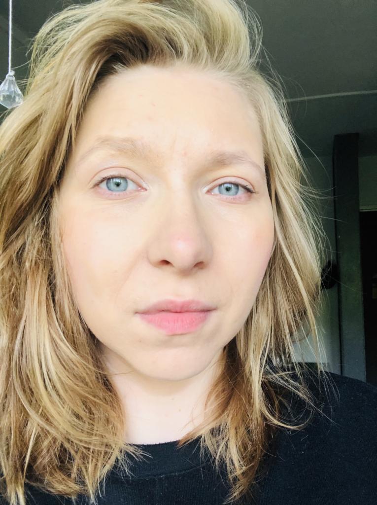 Portret kobiety z blond włosami i niebieskimi oczami, zbliżenie na twarz, widoczne delikatne podkreślenie makijażem, naturalne światło.