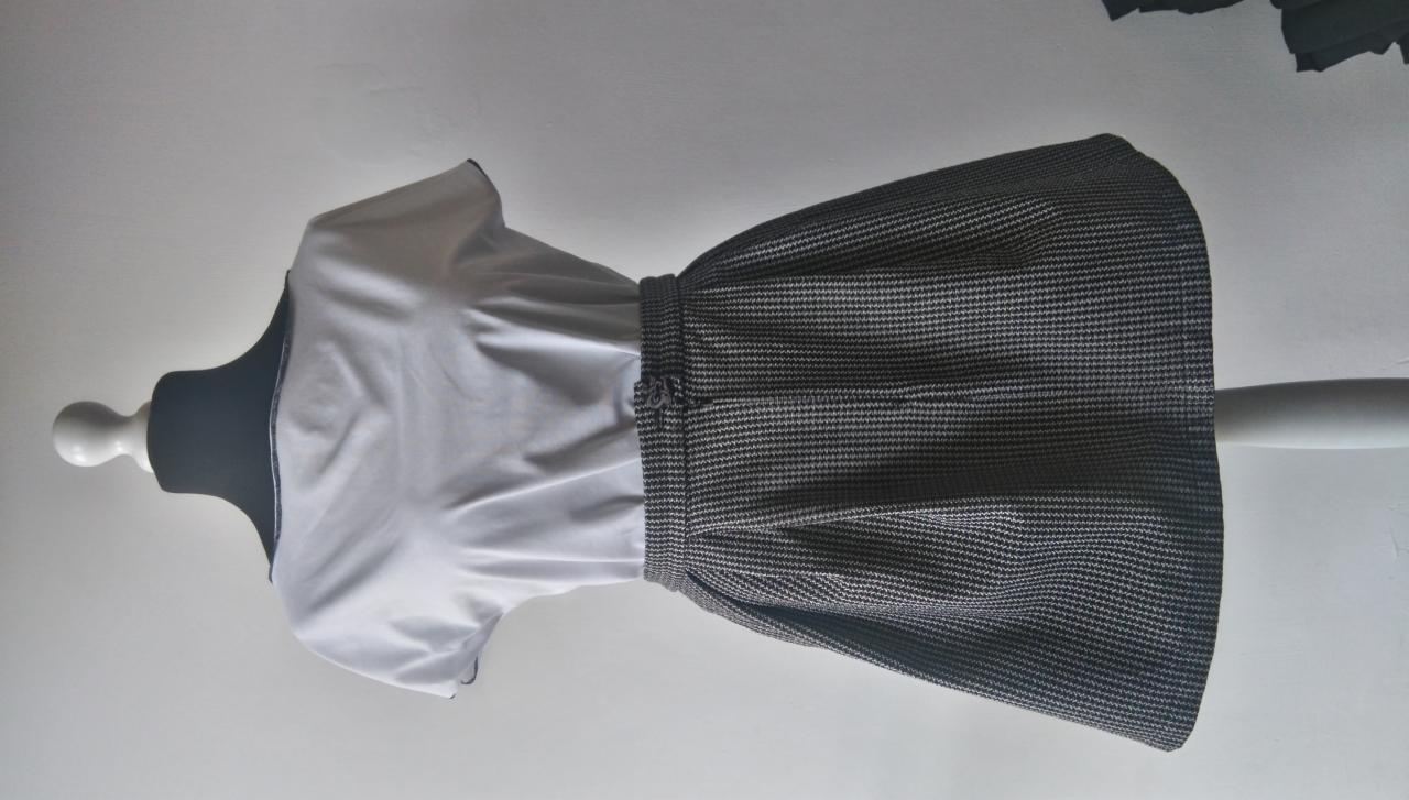 Sukienka z białą bluzką i spódnicą w pepitkę na manekinie krawieckim, widok z boku.