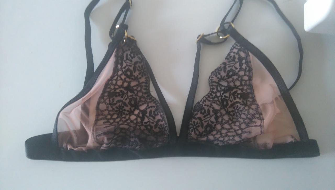 Czarny koronkowy biustonosz z cielistą podszewką i cienkimi ramiączkami na manekinie.