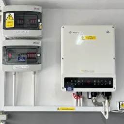 Rozdzielnice PV-DC i PV-AC oraz inwerter fotowoltaiczny zamontowane na ścianie z widocznymi przewodami i oznaczeniami ostrzegawczymi.