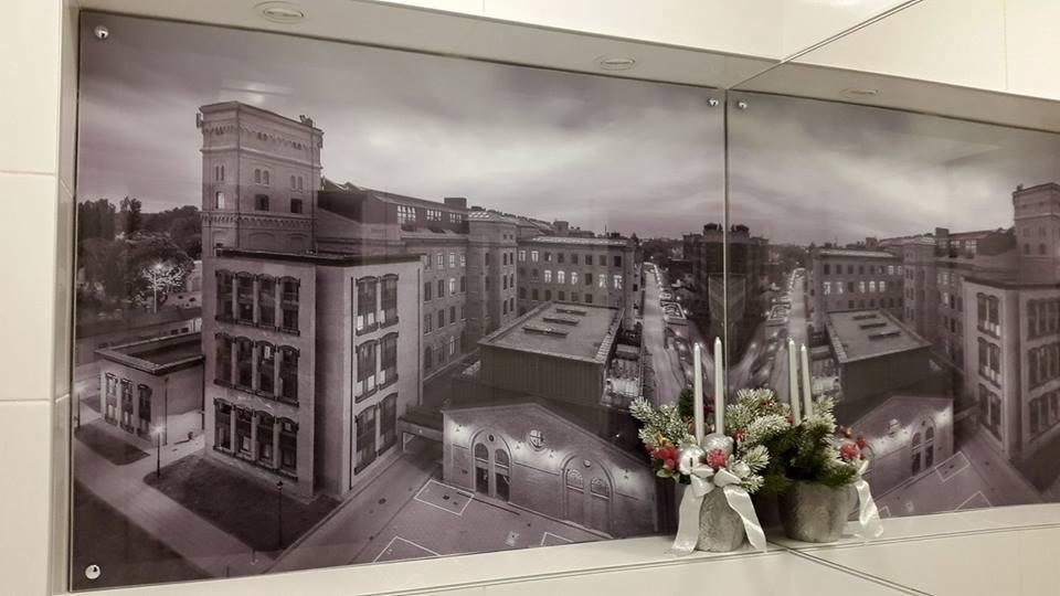 Czarno-biały wydruk wielkoformatowy przedstawiający panoramę miasta z perspektywy lotu ptaka, zamocowany na ścianie w łazience, z dekoracją świąteczną w dolnym rogu.