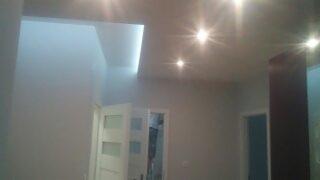 Wnętrze po remoncie: Jasne ściany, białe drzwi z przeszkleniami, oświetlenie punktowe w suficie podwieszanym, widok z dołu.