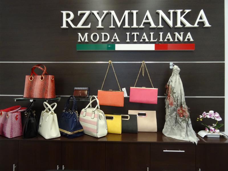 Ekspozycja torebek i akcesoriów w butiku z włoską modą, widoczne logo 'RZYMIANKA Moda Italiana' z motywem włoskiej flagi.