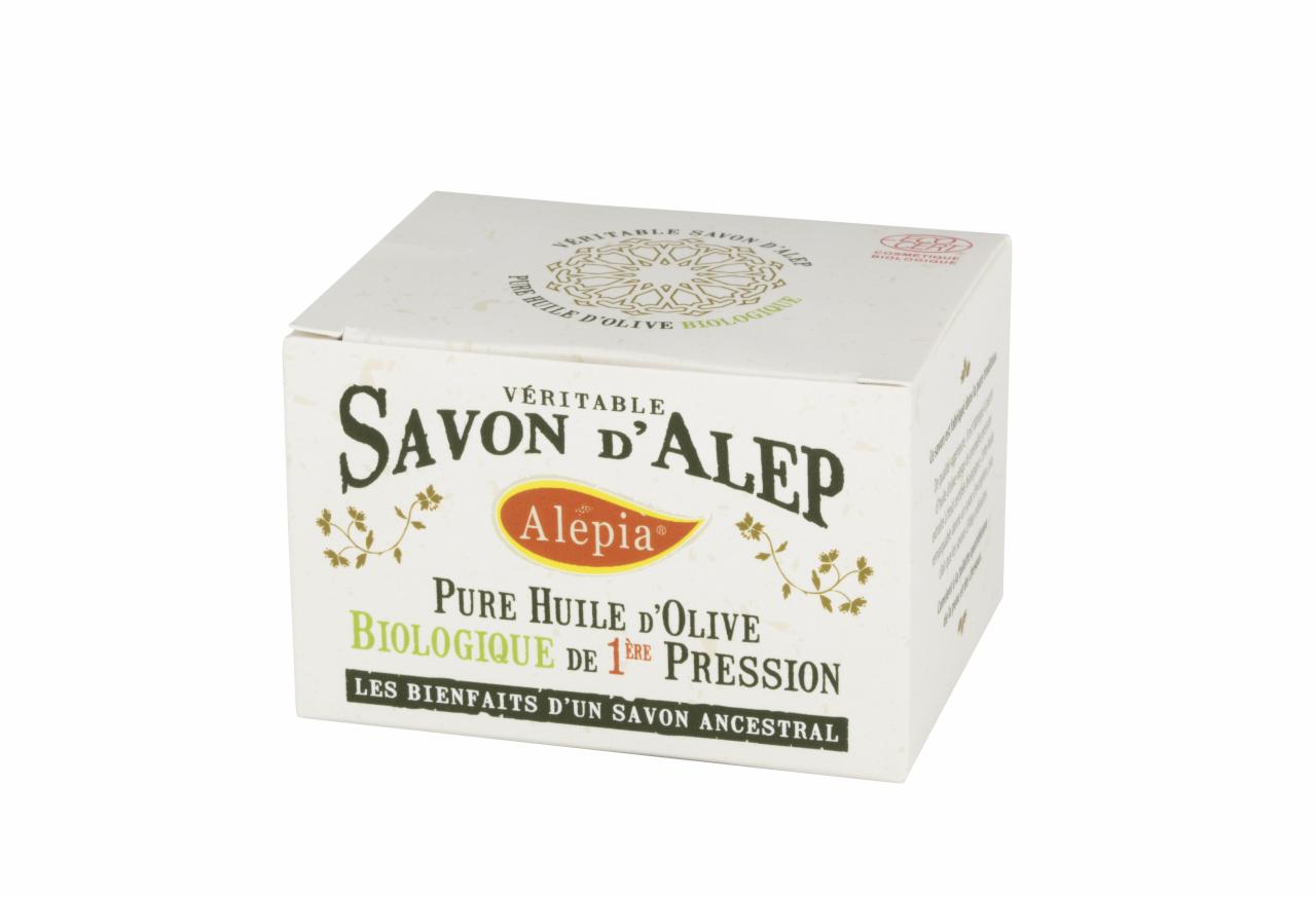 Kostka mydła Savon d'Alep w ozdobnym, białym opakowaniu z napisem w języku francuskim, informującym o zawartości oliwy z oliwek.