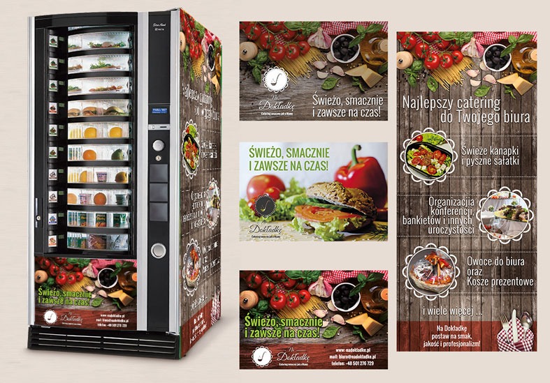Automat vendingowy z jedzeniem, oklejony grafiką cateringową 'Na Dokładkę', prezentujący ofertę: kanapki, sałatki, catering do biura, owoce i kosze prezentowe.