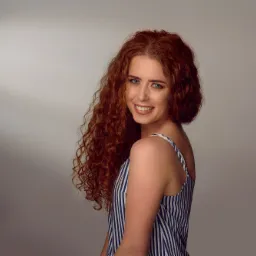 Portret uśmiechniętej modelki Weroniki Błaszak z burzą rudych loków, w bluzce w biało-niebieskie paski, wykonany w studiu fotograficznym w Kuślinie. Makijaż autorstwa Aleksandry Baszkowskiej...