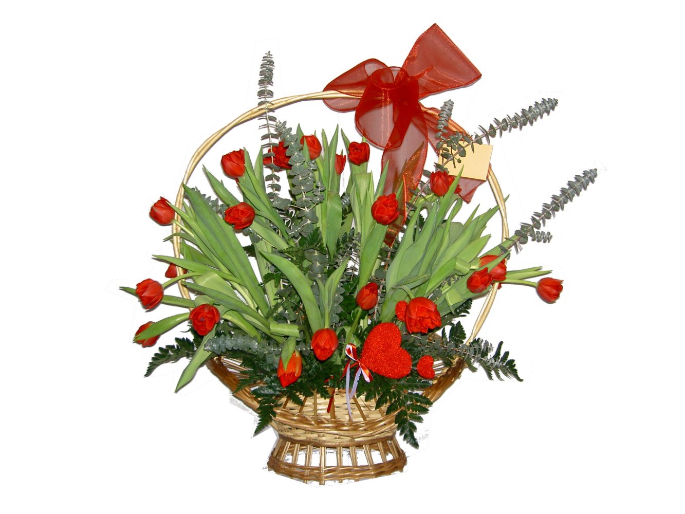 Kosz z czerwonymi tulipanami, ozdobiony czerwoną kokardą i brokatowym sercem, na białym tle.