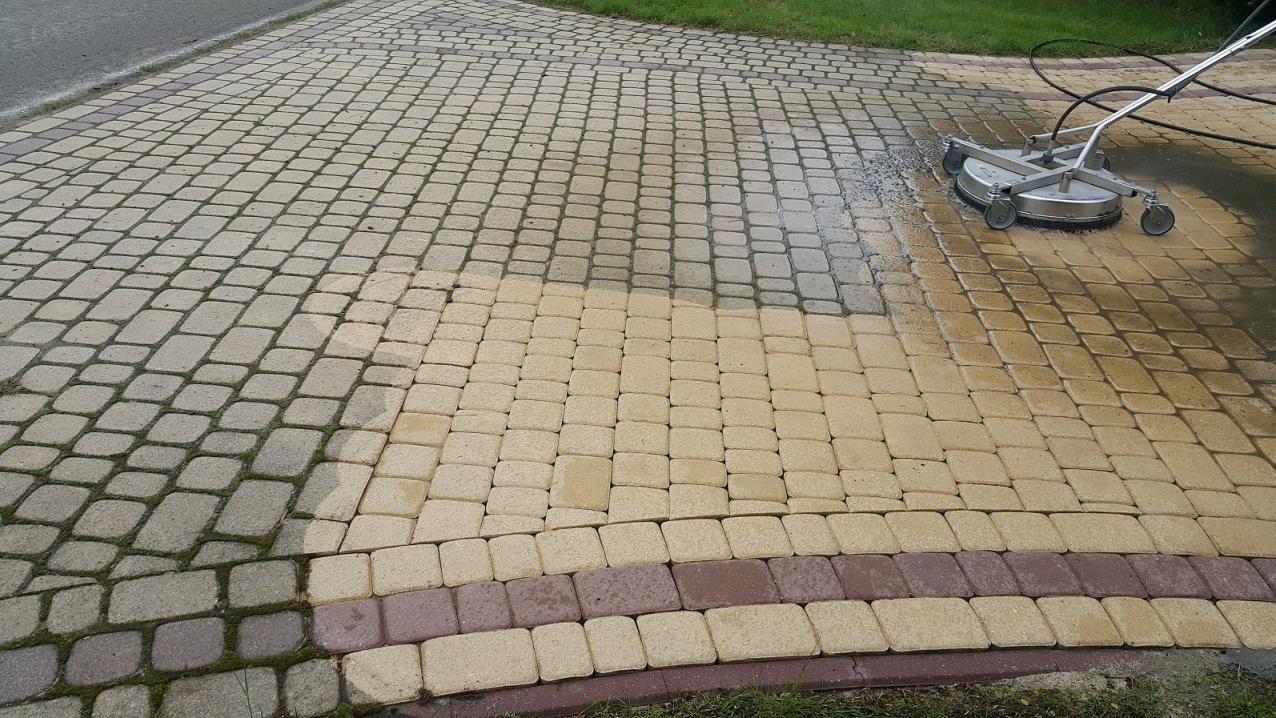 Czyszczenie kostki brukowej myjką ciśnieniową: widoczna różnica między czystą a brudną powierzchnią, zarys krawężnika i trawy.