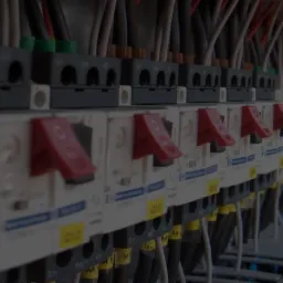 Szereg wyłączników nadprądowych w rozdzielnicy elektrycznej, widoczne przewody i oznaczenia obwodów.