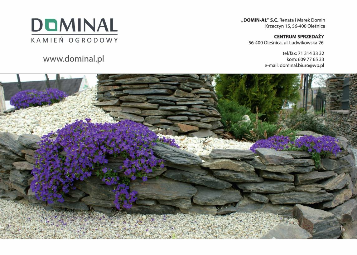 Ogród skalny z niską ścianką z łupka, obsadzony fioletowymi kwiatami smagliczki górskiej, wysypany białym grysem, widoczny logotyp firmy 'DOMINAL' oferującej kamień ogrodowy.