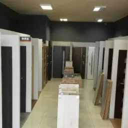 Ekspozycja różnych modeli w salonie sprzedaży, widoczne próbki kolorów i materiałów wykończeniowych.