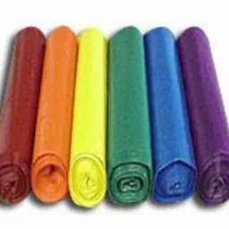 Rząd kolorowych worków na śmieci zwiniętych w rolki, ułożonych obok siebie: czerwony, pomarańczowy, żółty, zielony, niebieski, fioletowy. Widoczne cienie rzucane przez worki.