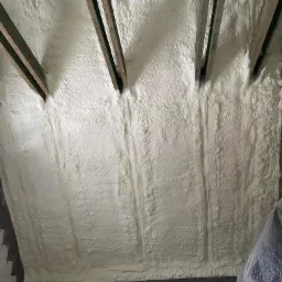 Poddasze po ociepleniu pianką PUR, widoczne drewniane krokwie. Aplikacja pianki pokryła całą powierzchnię, tworząc jednolitą warstwę izolacyjną.