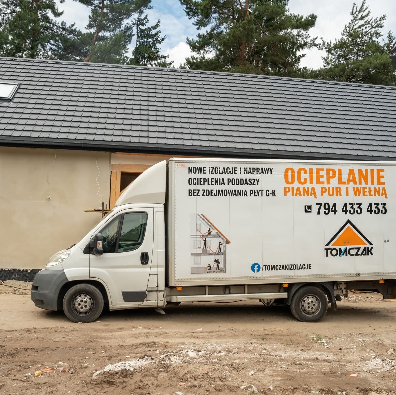 Samochód dostawczy z reklamą ocieplania pianą PUR i wełną, zaparkowany przed budynkiem z szarą dachówką. Widoczne drzewa w tle.