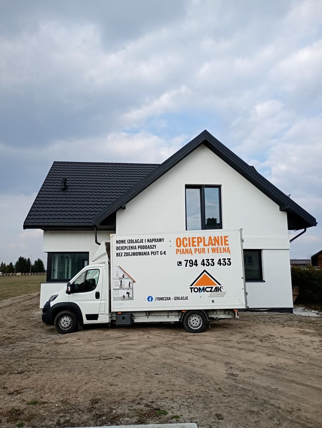 Biały samochód dostawczy z reklamą ocieplania pianą PUR i wełną stoi przed ocieplonym, nowoczesnym domem z ciemną dachówką i oknami. Usługa ocieplania.