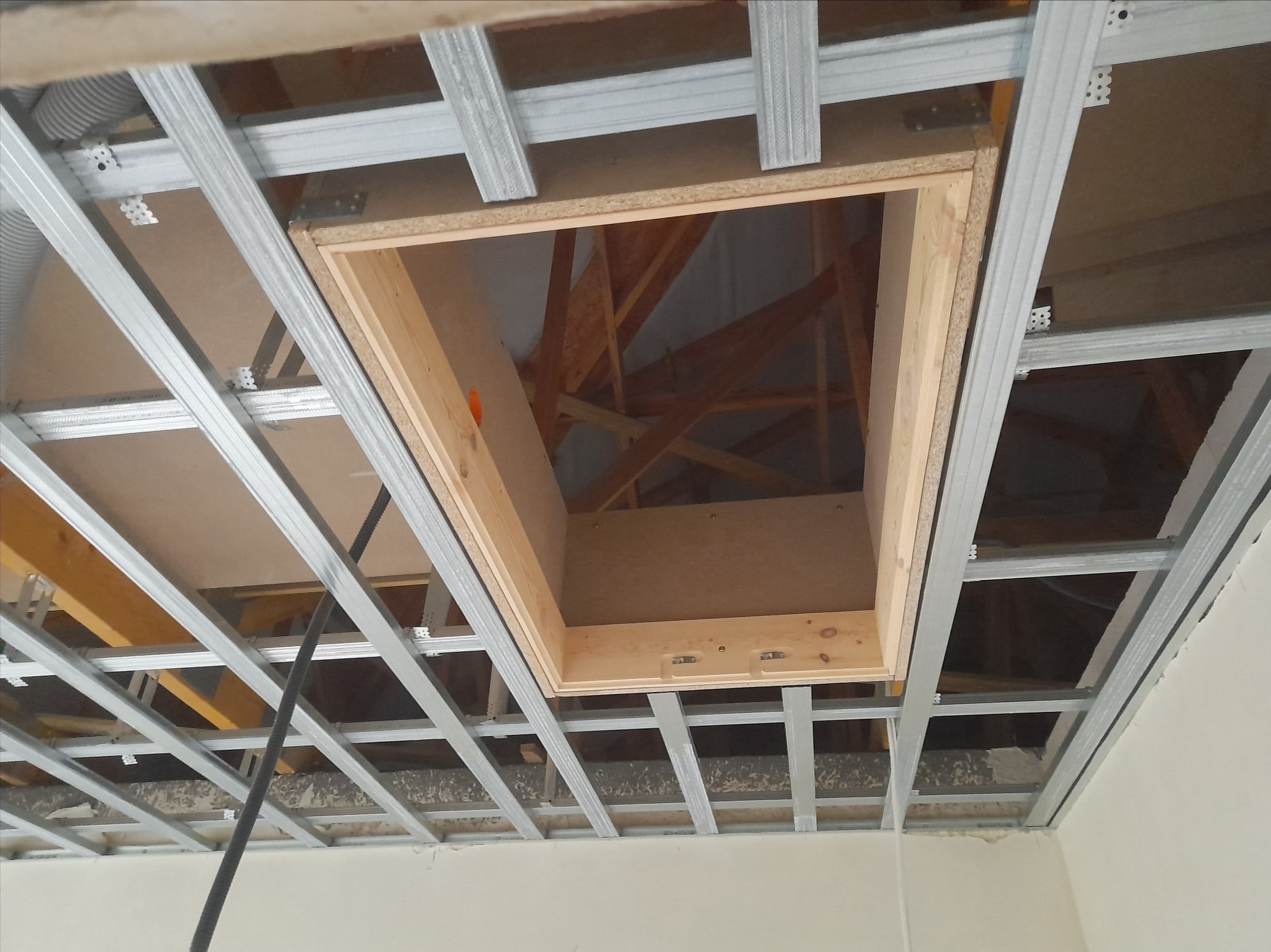 Stelaż sufitowy z zamontowanym drewnianym otworem rewizyjnym, widoczne elementy konstrukcji dachu.