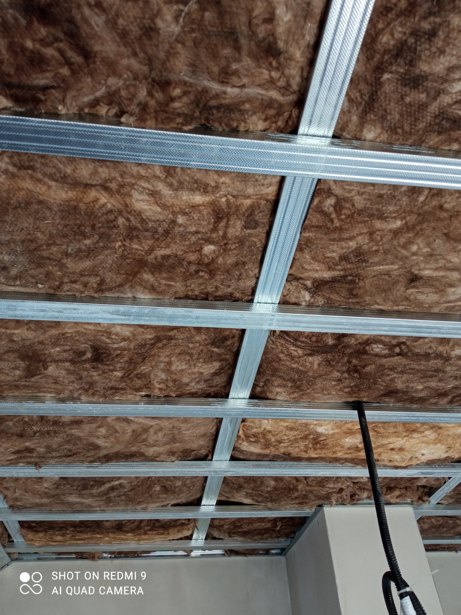 Montaż izolacji z wełny mineralnej w ruszcie metalowym pod płytę karton-gips na poddaszu