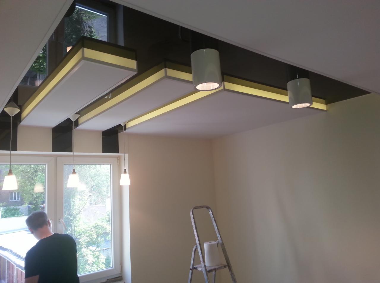 Nowoczesny sufit podwieszany z oświetleniem LED, widok z dołu, drabina oparta o ścianę, osoba przy oknie w tle.