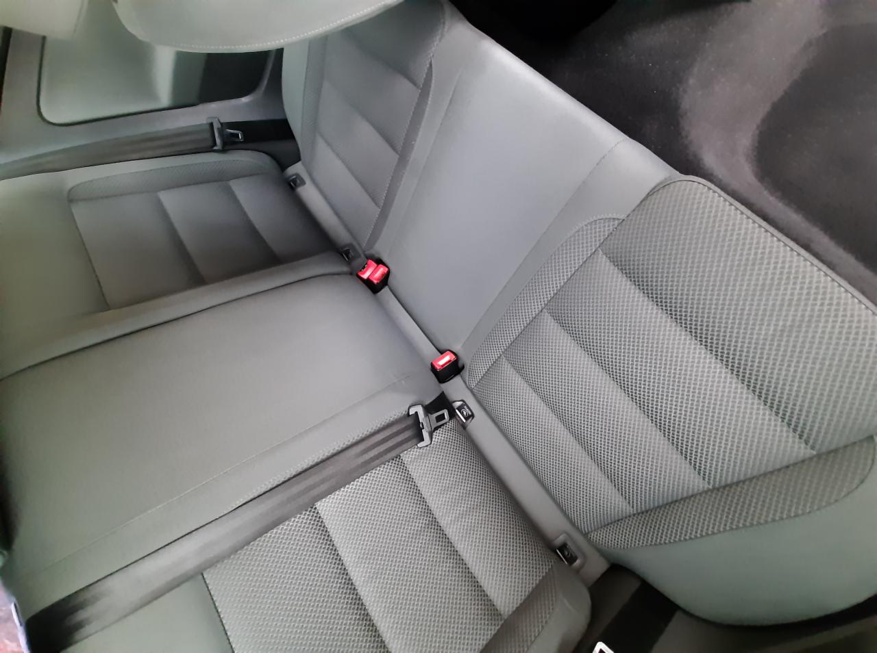 Szare, tekstylne tylne siedzenia samochodu z widocznymi pasami bezpieczeństwa i zagłówkami, ukazujące czystą tapicerkę po usłudze.
