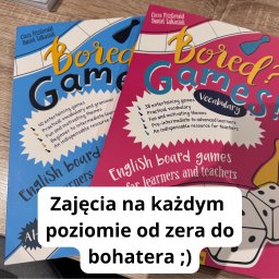 LinguaVision Edukacja & Języki - Dwa podręczniki do nauki języka angielskiego przez gry planszowe, jeden w kolorze niebieskim, drugi różowy, oba z tytułem 'Bored? Games!', na drewnianym stole.