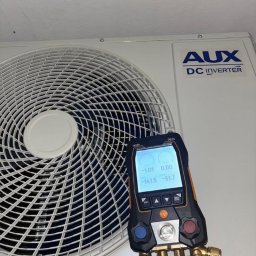 OPTIMAL-PLAST Rafał Pajdak - Biała klimatyzacja AUX DC Inverter z podłączonym cyfrowym manometrem Testo 557s, wskazującym wartości ciśnienia podczas serwisu.