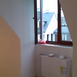 Ściana po szpachlowaniu i gładziowaniu w pokoju na poddaszu z oknem, widoczny grzejnik zabezpieczony folią