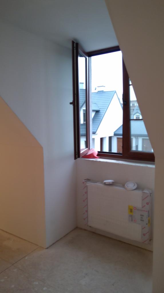 Ściana po szpachlowaniu i gładziowaniu w pokoju na poddaszu z oknem, widoczny grzejnik zabezpieczony folią