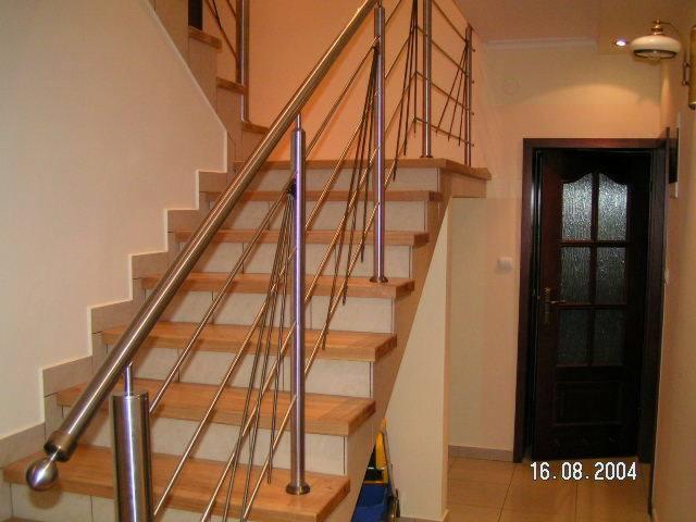 Schody drewniane z balustradą ze stali nierdzewnej, widok z dołu, fragment drzwi w tle