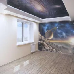 Pokój z fototapetą przedstawiającą kosmiczny krajobraz z planetą i galaktyką, drewniana podłoga, białe ściany i sufit z motywem kosmosu, oświetlenie punktowe.