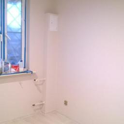 Renomex - Wnętrze pokoju po odświeżeniu ścian na jasny odcień, okno zabezpieczone taśmą malarską, podłoga wyłożona panelami w odcieniach bieli.