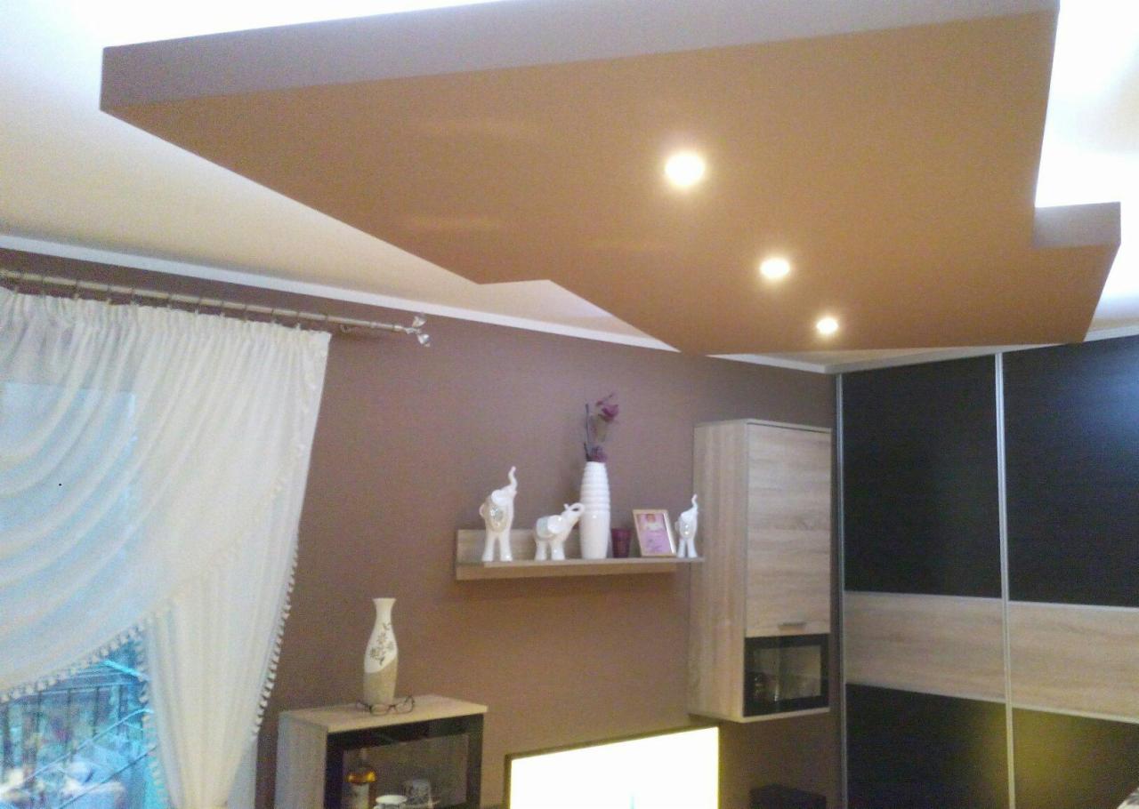 Sufit podwieszany z oświetleniem punktowym w salonie z brązowymi ścianami, zasłoniętym oknem i dekoracjami na półce.