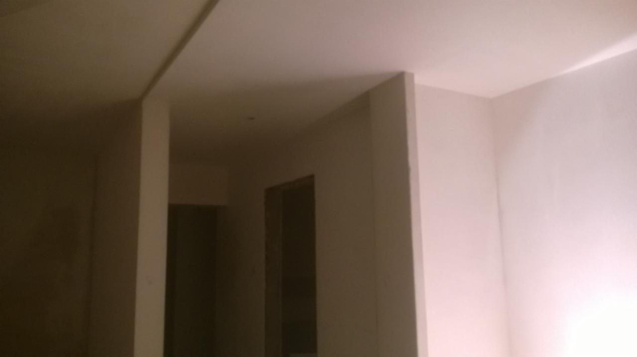 Wnętrze w trakcie prac wykończeniowych; widoczne ściany po szpachlowaniu, przygotowane do dalszych prac, z widocznymi przejściami między pomieszczeniami.