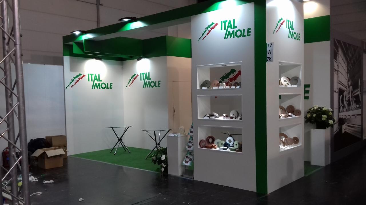 Aranżacja stoiska targowego firmy Ital Mole z ekspozycją produktów w białych wnękach, zielonymi akcentami i logo firmy na ścianach.