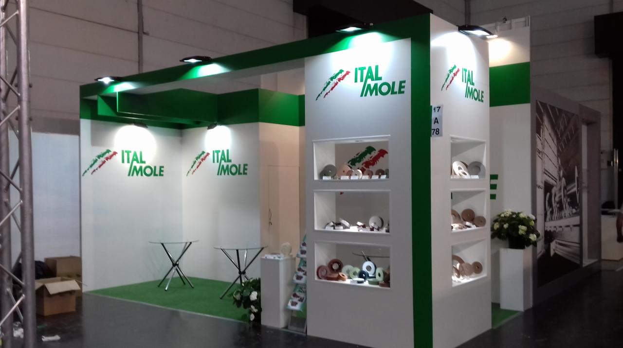 Stoisko targowe firmy Ital Mole z ekspozycją tarcz ściernych w podświetlanych gablotach, biało-zielona kolorystyka, logo firmy widoczne na ścianach.