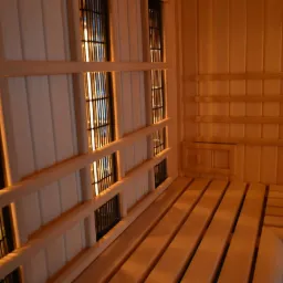 Wnętrze sauny infrared z drewnianymi ławkami i panelami grzewczymi widocznymi za drewnianą konstrukcją.