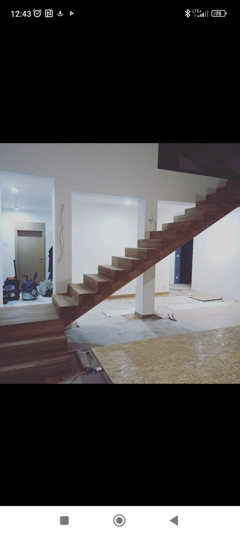 Surowe, drewniane schody bez poręczy, w trakcie montażu w przestronnym, jasnym wnętrzu. Podłoga zabezpieczona płytami OSB, widoczne narzędzia i materiały budowlane w tle.