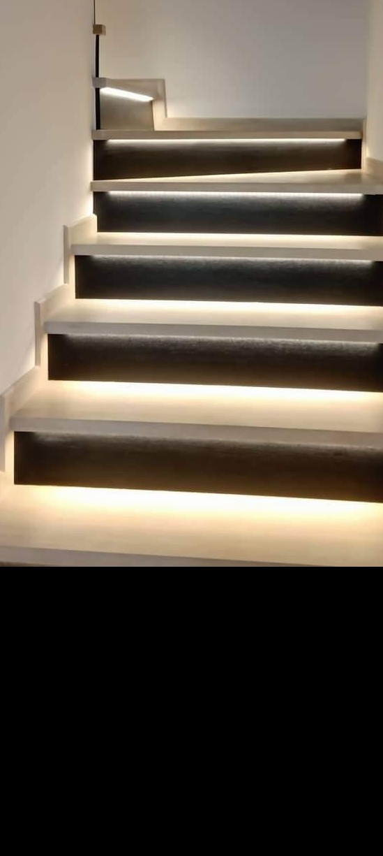 Nowoczesne schody z podświetleniem LED pod każdym stopniem, widok z dołu, minimalistyczny design.