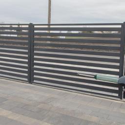 GERMAPLAN System Sp. z o.o. - Automatyczna brama wjazdowa z poziomymi panelami w Gorzowie Wielkopolskim, widoczne siłowniki i kostka brukowa.