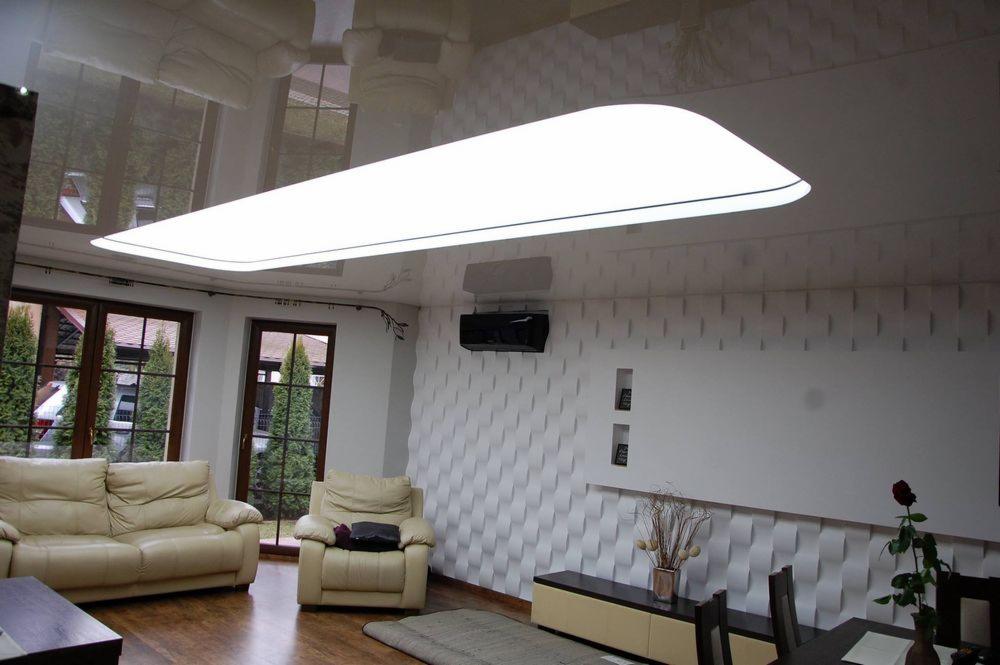 Jasny salon z beżową sofą, fotelem i dywanem, na ścianie dekoracyjne panele 3D oraz podwieszany sufit z oświetleniem LED.