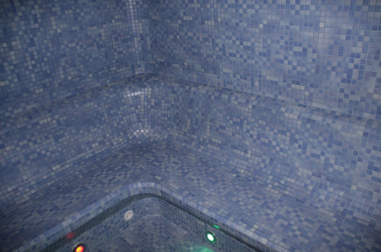 Wnętrze wyłożone mozaiką w odcieniach błękitu, z oświetleniem punktowym w dolnej części.