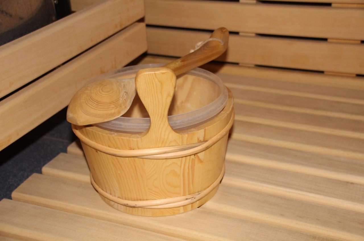 Drewniany ceber z chochlą wewnątrz, w tle drewniane deski sauny.