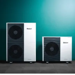 Dwie jednostki pompy ciepła Vaillant aroTHERM plus, różniące się wielkością, ustawione obok siebie na ciemnej podłodze przed turkusową ścianą.