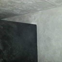 DecorLine - Fragment ściany i sufitu po nałożeniu dekoracyjnej, szarej struktury przypominającej beton i czarnej ściany z efektem połysku, widoczne niedoskonałości i nierówności.