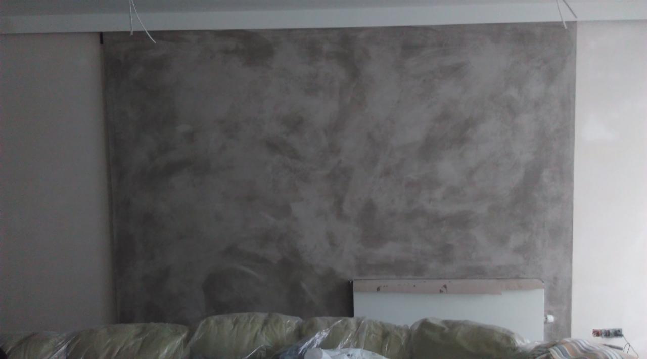 Ściana z efektem dekoracyjnym w odcieniach szarości, częściowo zakryta folią ochronną, widoczne przewody pod sufitem.